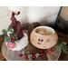 This is Crumble the Elf with his hat off, placed next to him. You can see the inside of the gourd is unfinished. Jingle bells lay nearby. 
